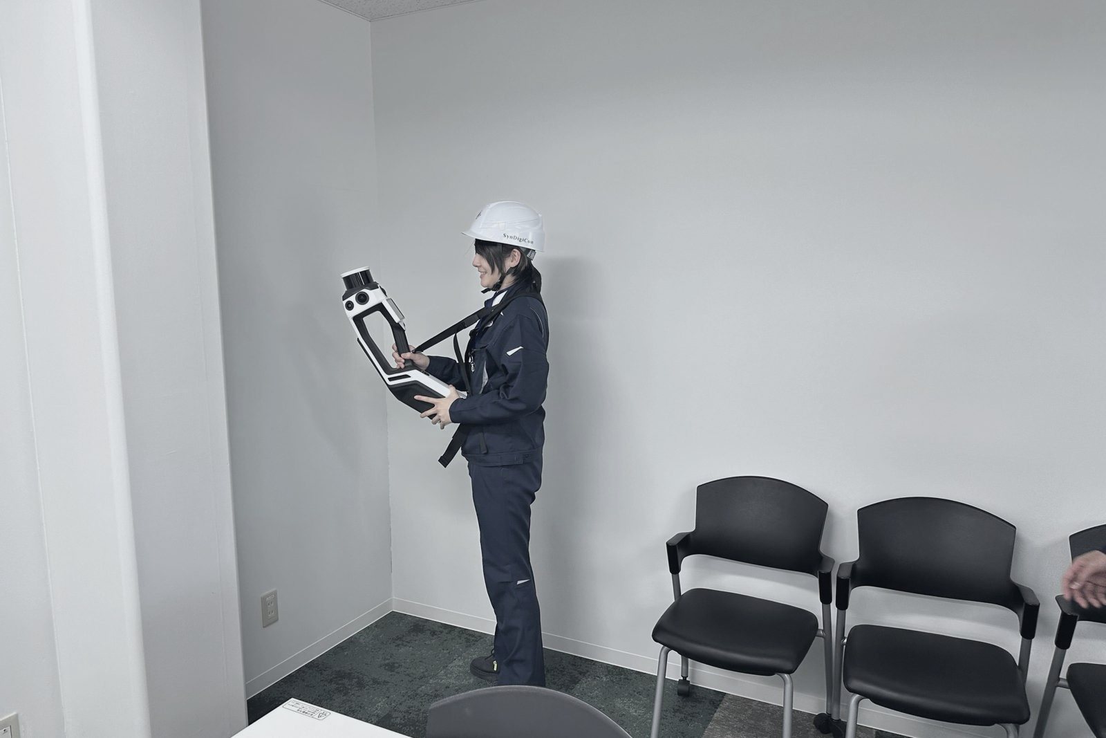 室内で壁際を3Dスキャンする社員