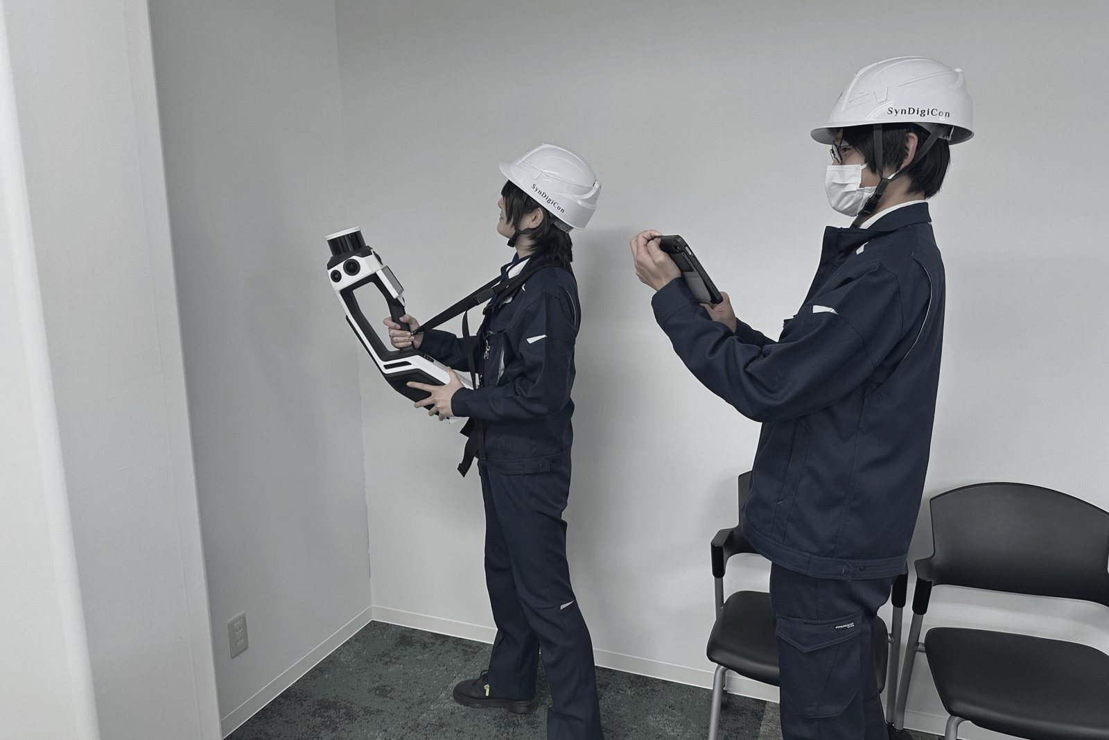 スキャナとタブレットを持って2人で作業する社員